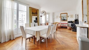 A dining area with a white table and chairs, a large mirror, and a fireplace.