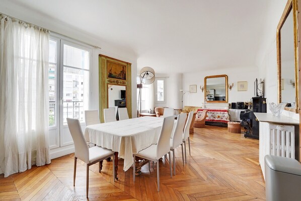Un coin repas avec une table et des chaises blanches, un grand miroir et une cheminée.
