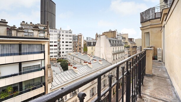 A multi-story residential building with balconies, a mix of architectural styles, and a clear sky.