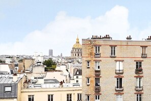 Une vue urbaine avec, au loin, un bâtiment imposant surmonté d’un dôme doré, entouré d’immeubles aux balcons et aux fenêtres bien visibles.