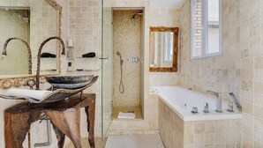 Een badkamer met een grote spiegel, een wastafel, een douche en een bad.