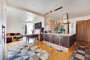A modern kitchen with a central island, bar stools, and pendant lighting. - Nice 90m² - 2 bdr near Champs-Élysées, air-con. (Neuilly-sur-Seine)