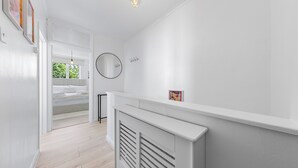 A hallway with a radiator, a round mirror, and a picture frame on the wall. - Charming London Apartment Near City Center (London)