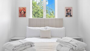 A neatly made bed with white linens, two bedside tables, and two framed artworks on the walls. - Charming London Apartment Near City Center (London)