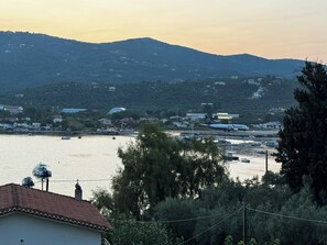 A coastal town with a marina, a large airplane on the runway, and hills in the background.