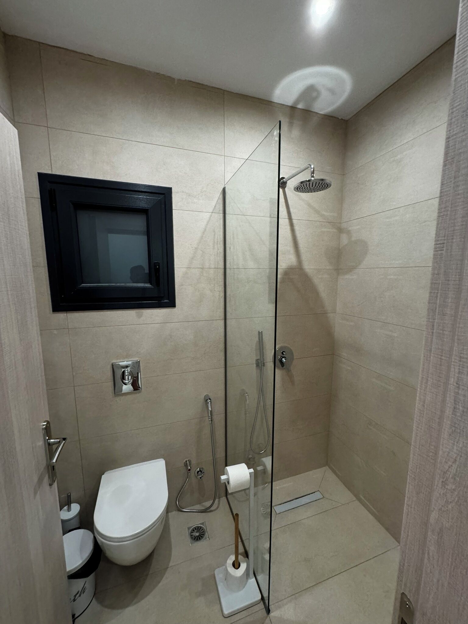 A modern bathroom with a glass-enclosed shower, a toilet, and a bidet.