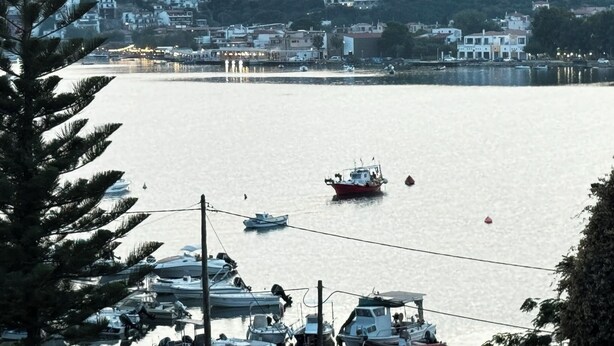 A marina with boats docked, a mountainous backdrop, and buildings in the distance. - Georgias House Project North (Skiathos)