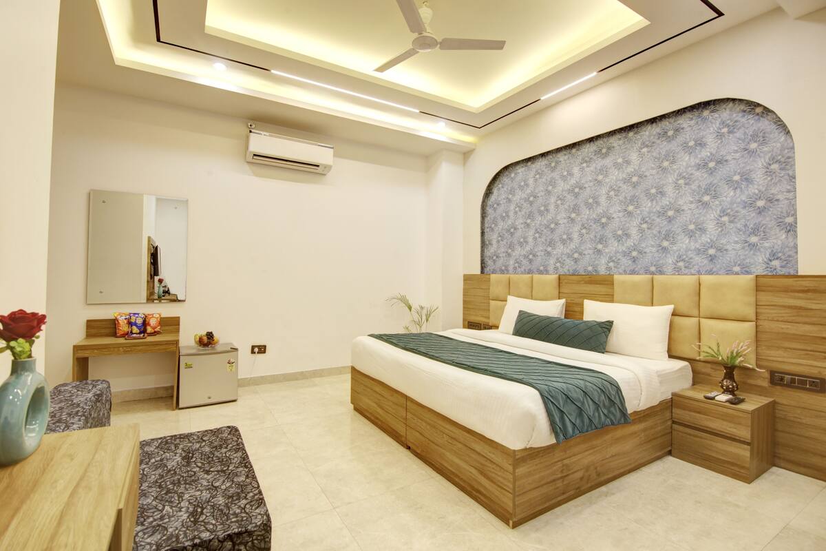 A modern bedroom with a bed, bedside tables, a desk, and a vanity.