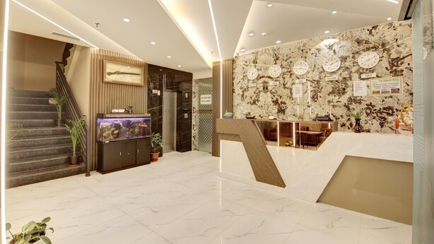 A modern hotel lobby with a marble floor, a reception desk, a fish tank, and a staircase. - Hotel Armani Suites (New Delhi)
