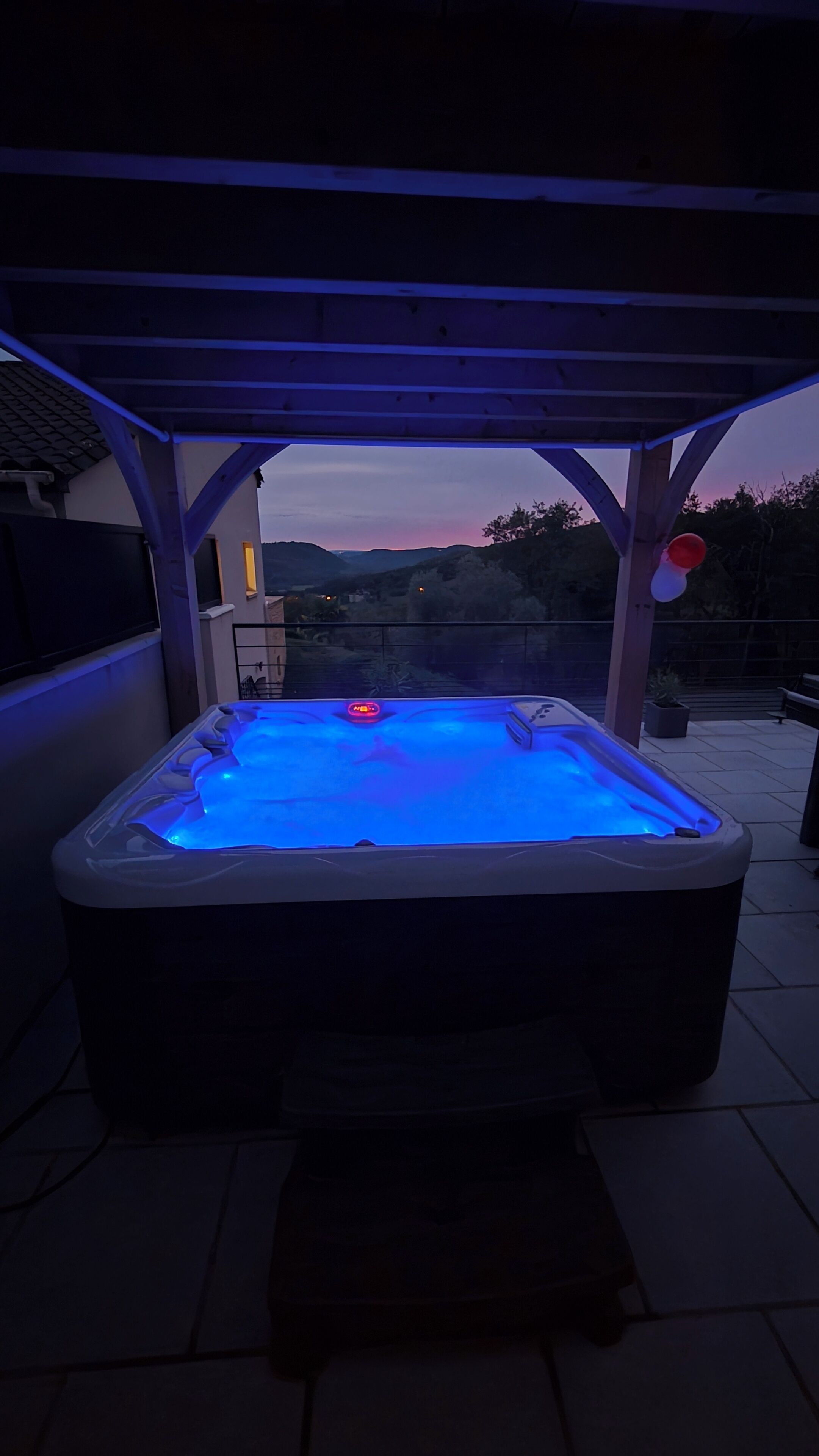 A hot tub under a covered patio with a view of the landscape.
