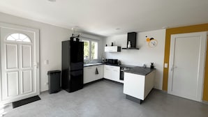 A modern kitchen with white cabinetry, a black refrigerator, and a microwave. - House with private spa and view of the Dordogne valley (Pechs-de-l'Espérance)