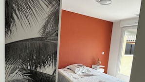 A bedroom with a bed, a nightstand, a wall with a palm tree mural, and a window with a view of the outside. - House with private spa and view of the Dordogne valley (Pechs-de-l'Espérance)