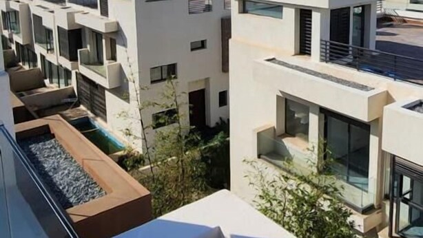 Een modern woongebied met meerdere appartementencomplexen, een zwembad op het dak en uitzicht op de oceaan.