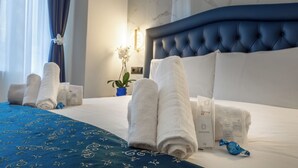 A neatly made bed with rolled white towels, a blue patterned bedspread, and a dental kit on the side. - MISS SUITE  (Rome)