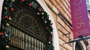A building facade with a decorative wrought iron gate, a Christmas wreath, and a hotel sign. - MISS SUITE  (Rome)