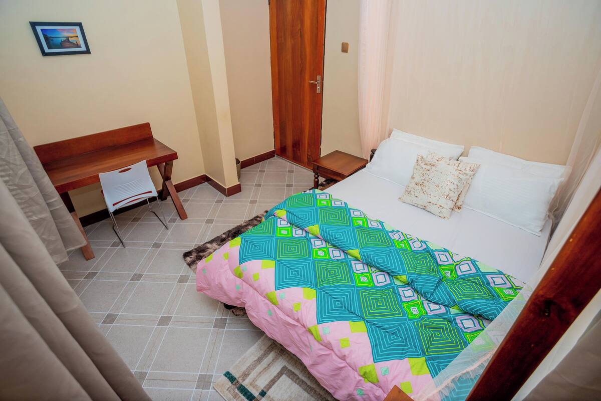 A bedroom with a bed, a desk, and a door.