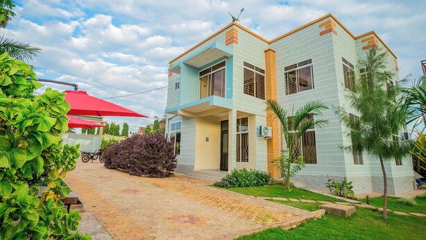 A two-story house with a tiled driveway and a small garden. - Kilimanjaro Home Of Travelers (Moshi)
