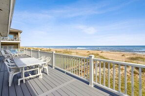 Une terrasse avec une table et des chaises donnant sur une plage.