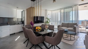 A modern kitchen with a dining area, a sofa, and a view of the city. - Torre Sakura (Benidorm)