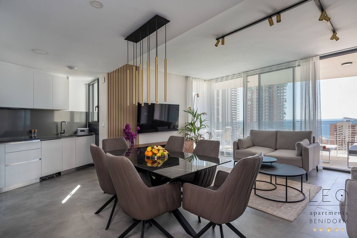 Uma cozinha moderna com área de refeições, um sofá e vista para a cidade.