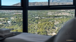 Vista dalla finestra con una montagna sullo sfondo, un paesaggio verde sottostante e il testo "LEC apartment BENITO" ben visibile.