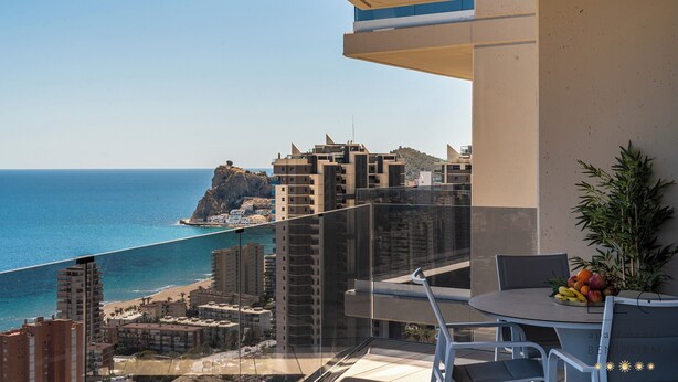 A balcony with a glass railing overlooking a beach and cityscape. - Torre Sakura (Benidorm)