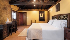 Une chambre à coucher avec un lit en bois, une commode, une chaise et un mur en pierre.