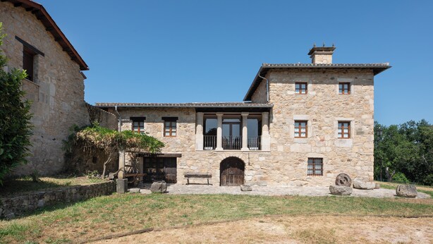 Un bâtiment en pierre doté d’un balcon, d’une grande porte en bois et d’une petite fenêtre.