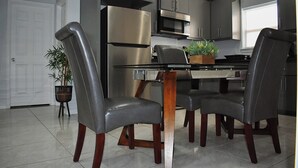 A modern kitchen with a dining table, chairs, and a refrigerator.