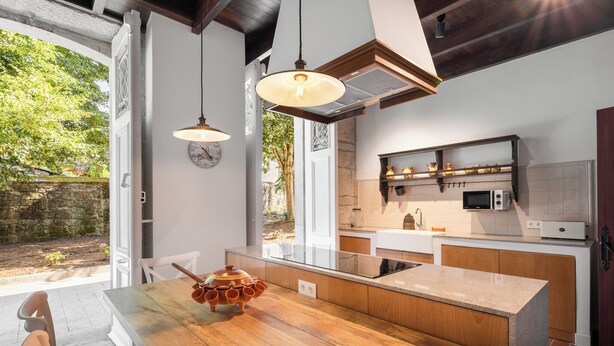 Une cuisine moderne avec un îlot central en bois, des luminaires suspendus et une vue sur l’extérieur.