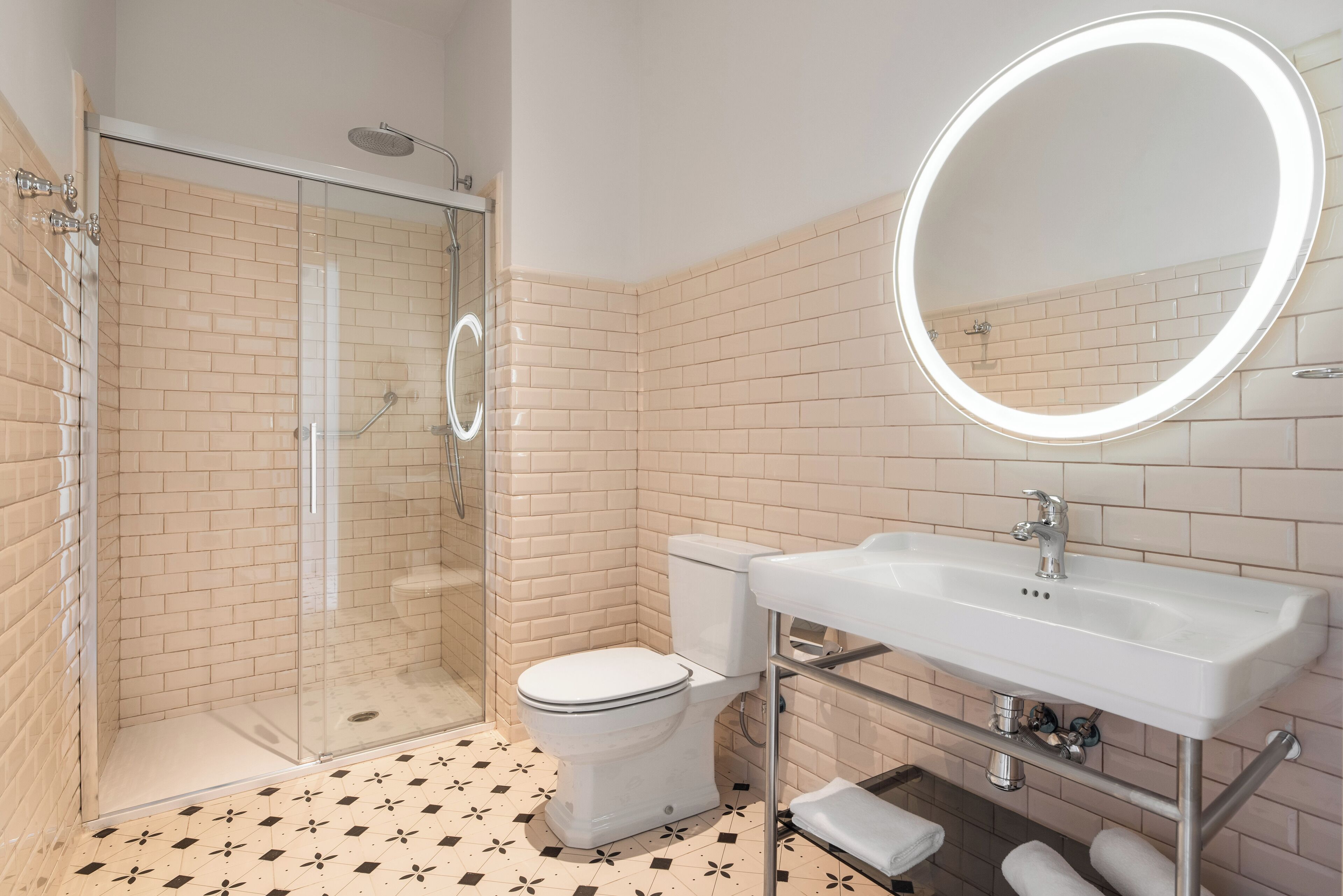 Un baño moderno con ducha de vidrio, inodoro blanco y lavamanos con espejo.
