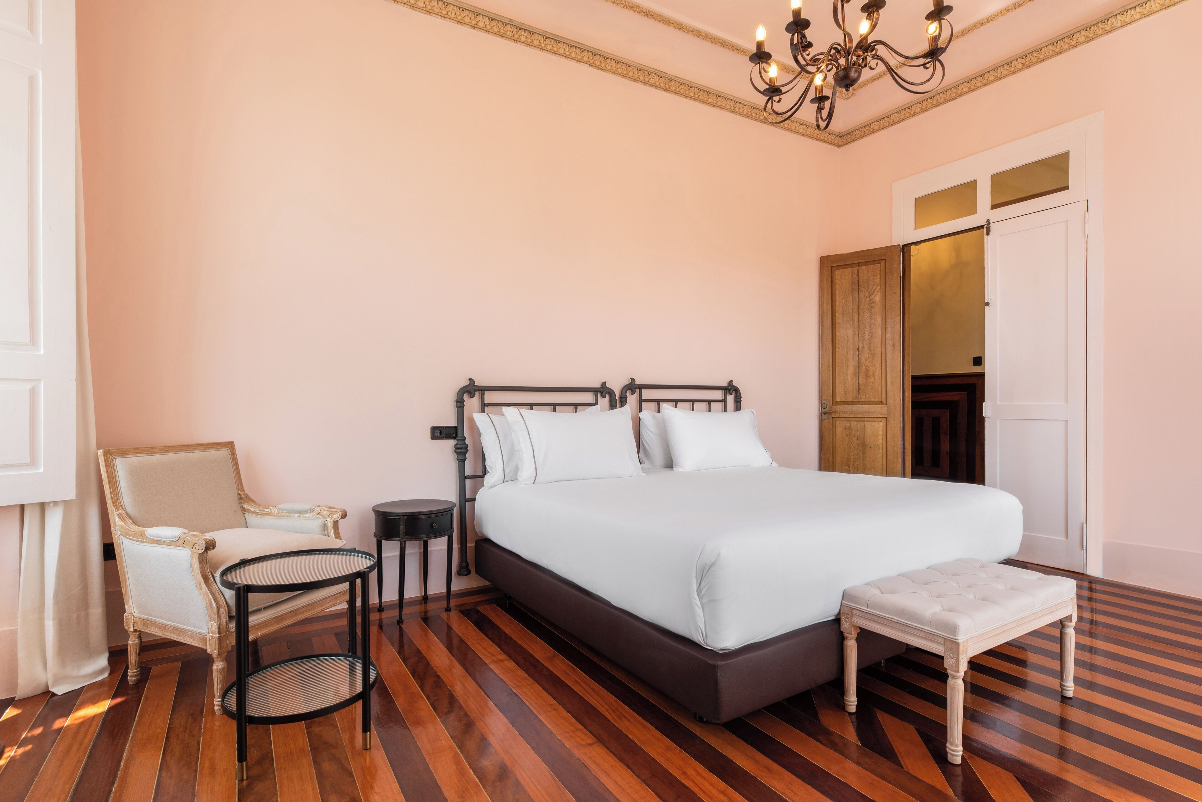 Ein Schlafzimmer mit einem großen Bett, einem Sessel, einem runden Tisch und einer Bank.