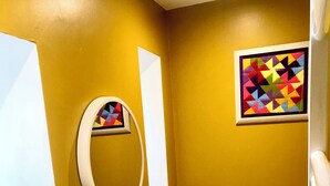 A bathroom with a sink, toilet, and a mirror. There is a colorful artwork on the wall. - Stylish annexe in Caernarfon (Caernarfon)