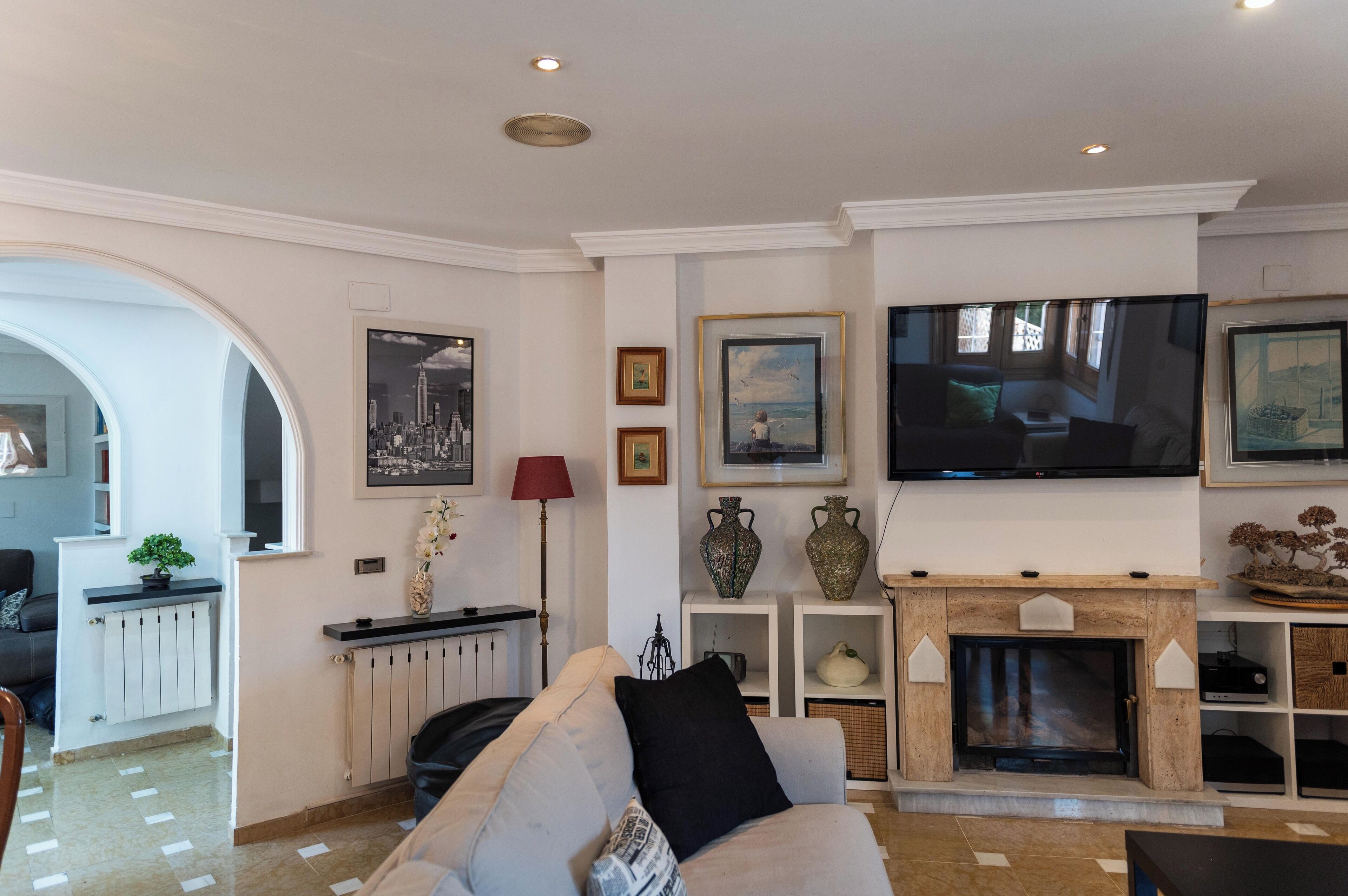 Ein Wohnzimmer mit Kamin, Fernseher und verschiedenen gerahmten Kunstwerken an den Wänden.