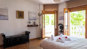 A hotel room with a bed, a bench, a floor lamp, and a view of greenery through the door. - Piscina, gym,2 barbacoas, vistas a Sierra Nevada desde terraza en ático de 60m2  (Peligros)