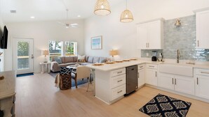 Una cocina moderna con armarios blancos, una isla central e iluminación colgante.