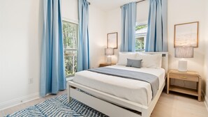 Ein Schlafzimmer mit einem Bett, Nachttischen, einem Deckenventilator und Vorhängen.