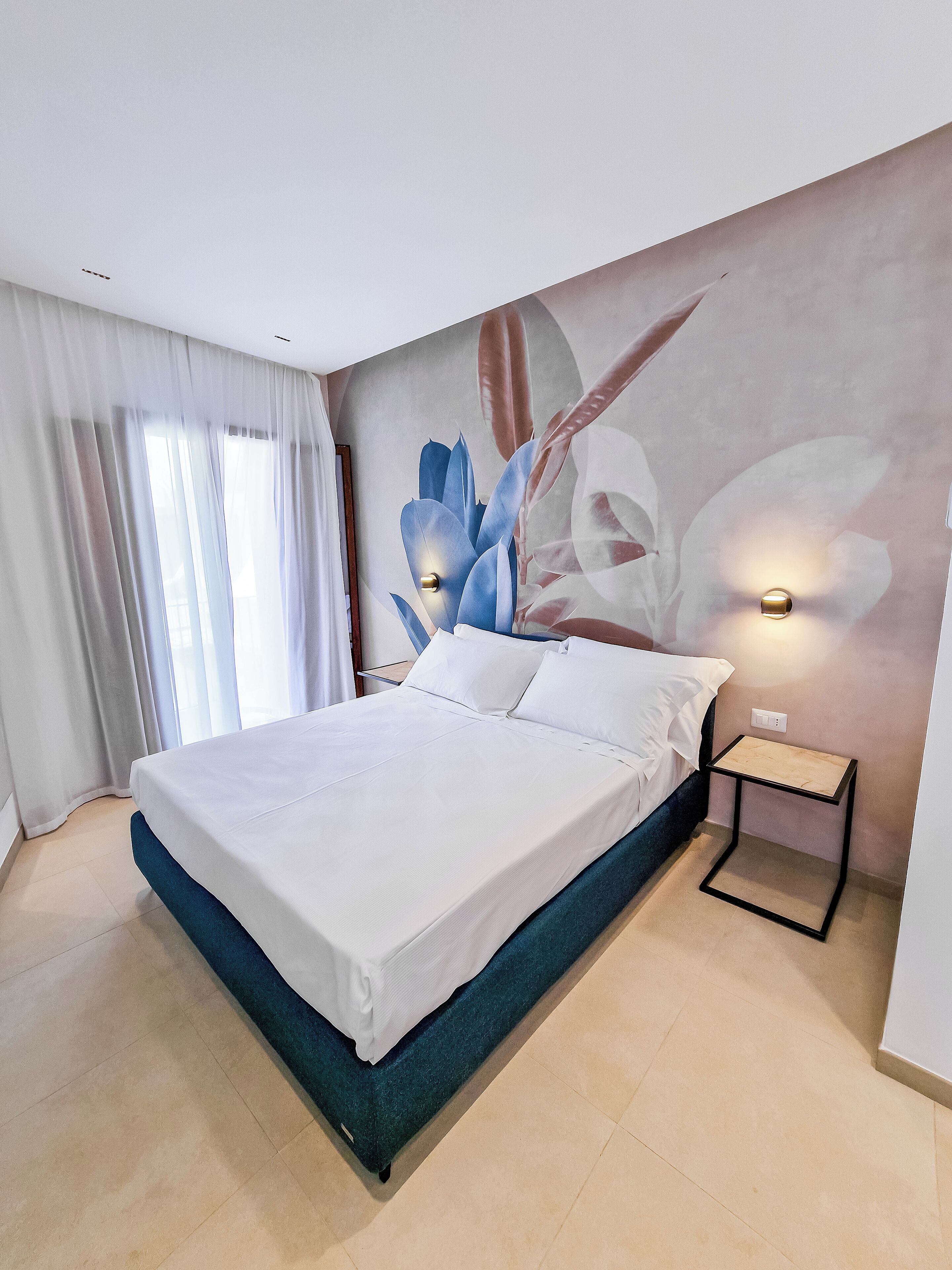 Een moderne slaapkamer met een groot bed, een nachtkastje en een wandlamp.