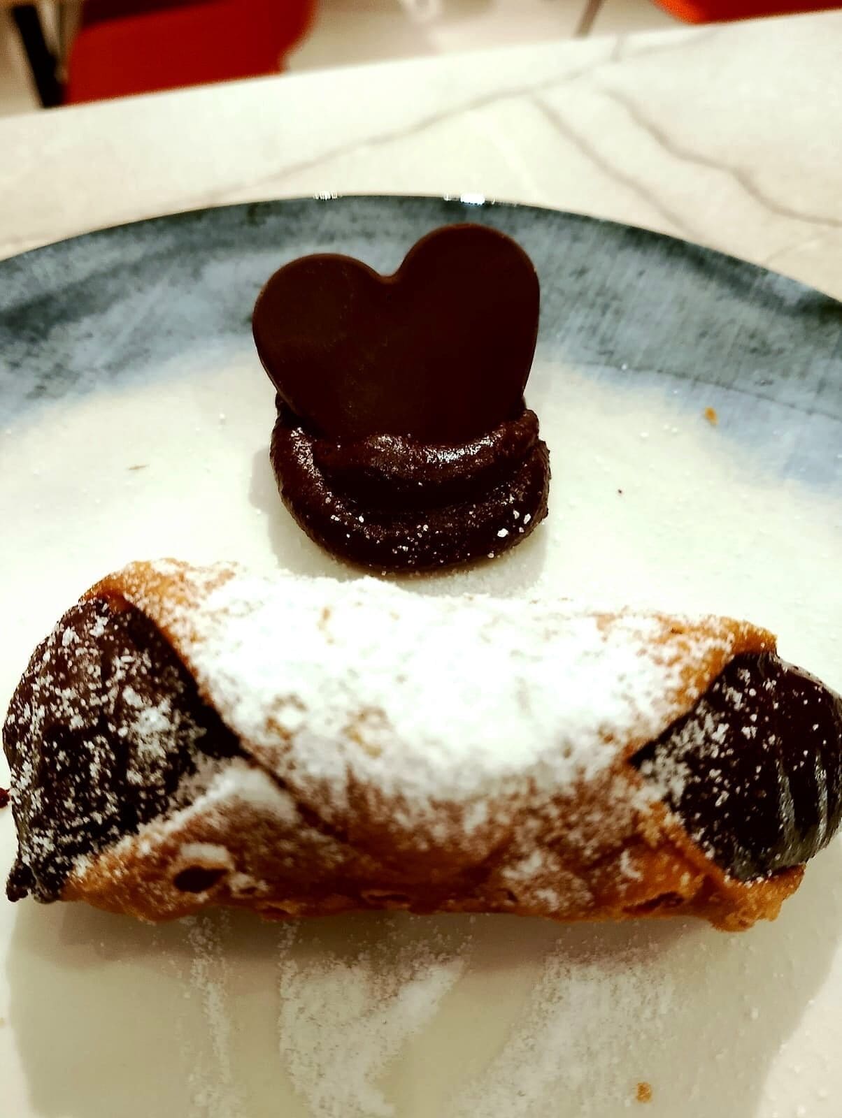 Un dessert con un pezzo di cioccolato a forma di cuore su un piatto.