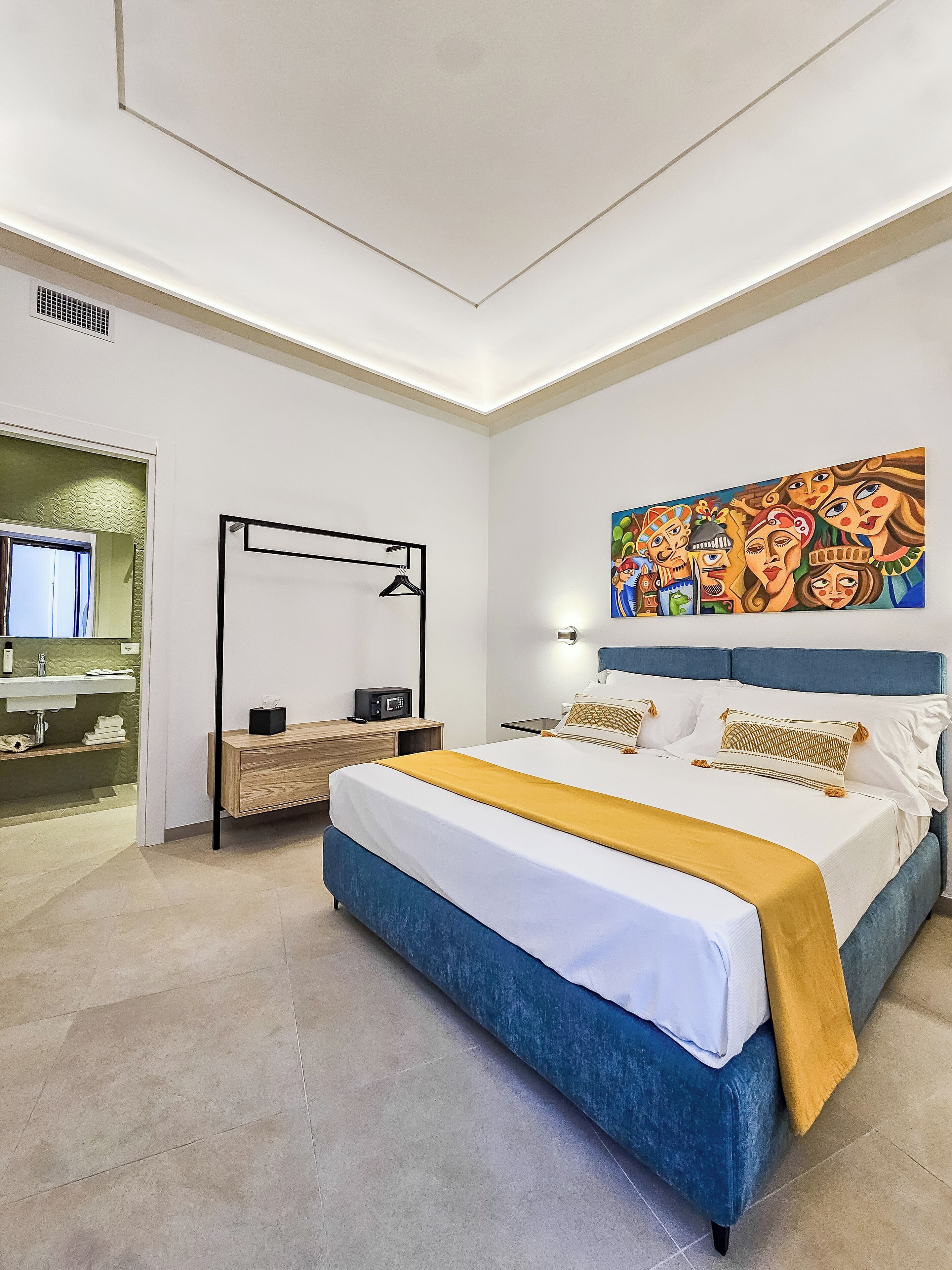 Quarto moderno com uma cama grande, mesa de cabeceira, espelho e um quadro na parede.