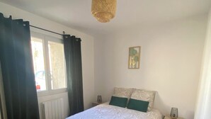 Une chambre à coucher avec un lit en bois, une table de chevet, une lampe et une fenêtre avec des rideaux.