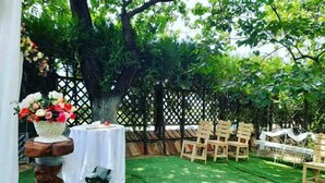 An outdoor seating area with a table and chairs, surrounded by a wooden fence and trees. - Safari House (Tbilisi)
