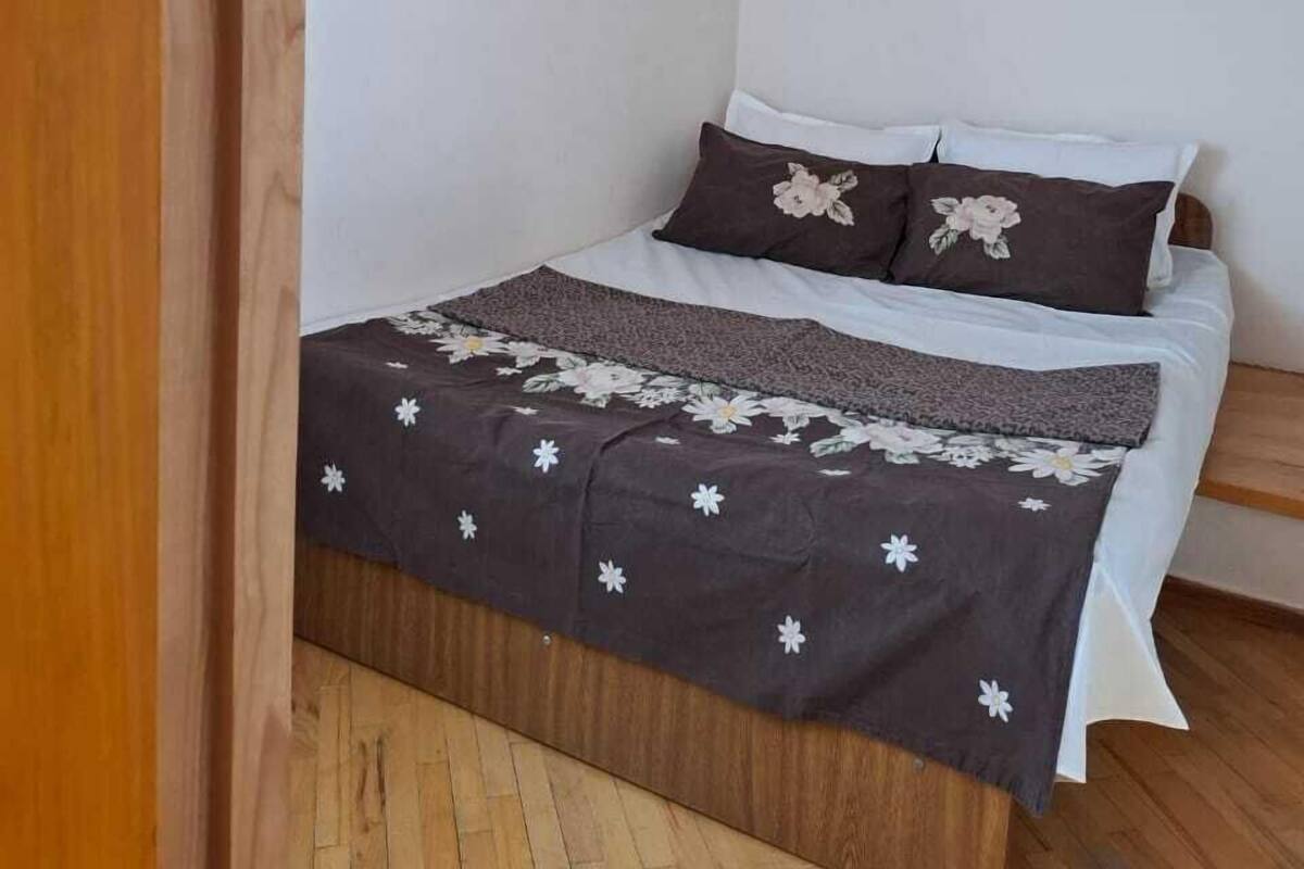 A bedroom with a sloped ceiling, a bed with floral bedding, and a wooden floor.