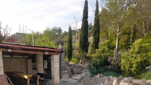 A rectangular swimming pool with a textured blue edge, surrounded by a stone wall and greenery. - Safari House (Tbilisi)