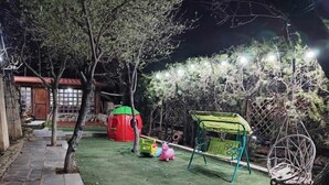A nighttime outdoor area with a paved walkway, a swing set, a playhouse, and a small garden area. - Safari House (Tbilisi)