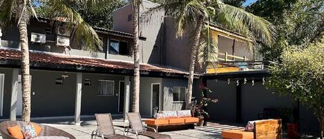 Una casa moderna con piscina, mobiliario exterior y palmeras.