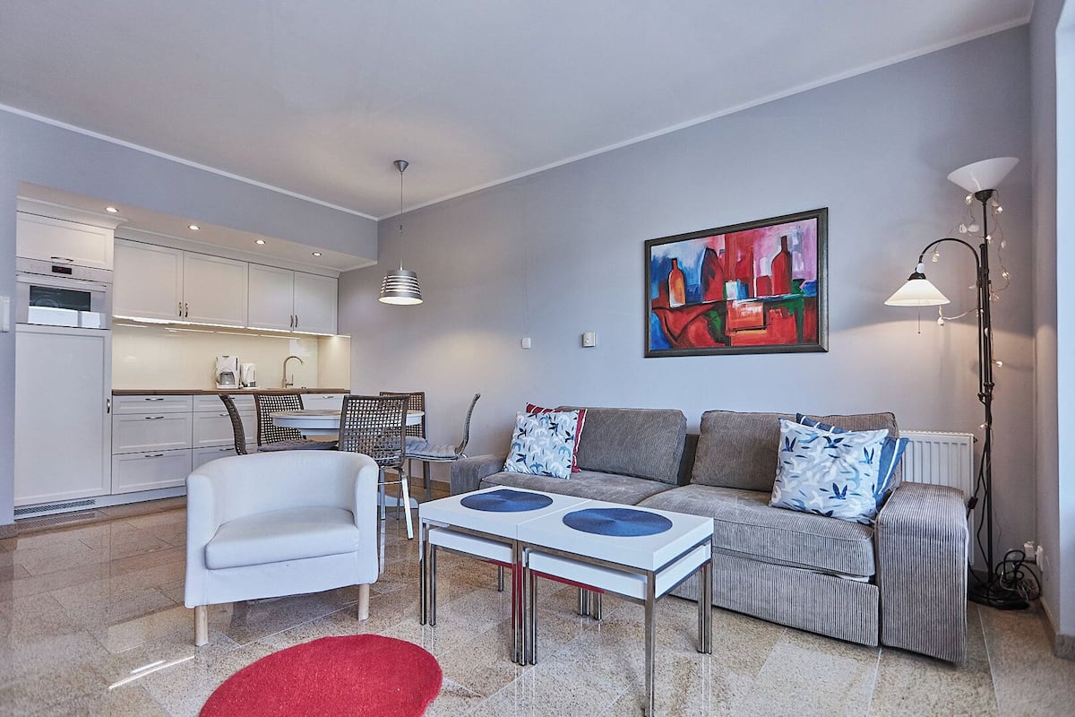 A modern living room with a sofa, a coffee table, and a dining area with chairs.