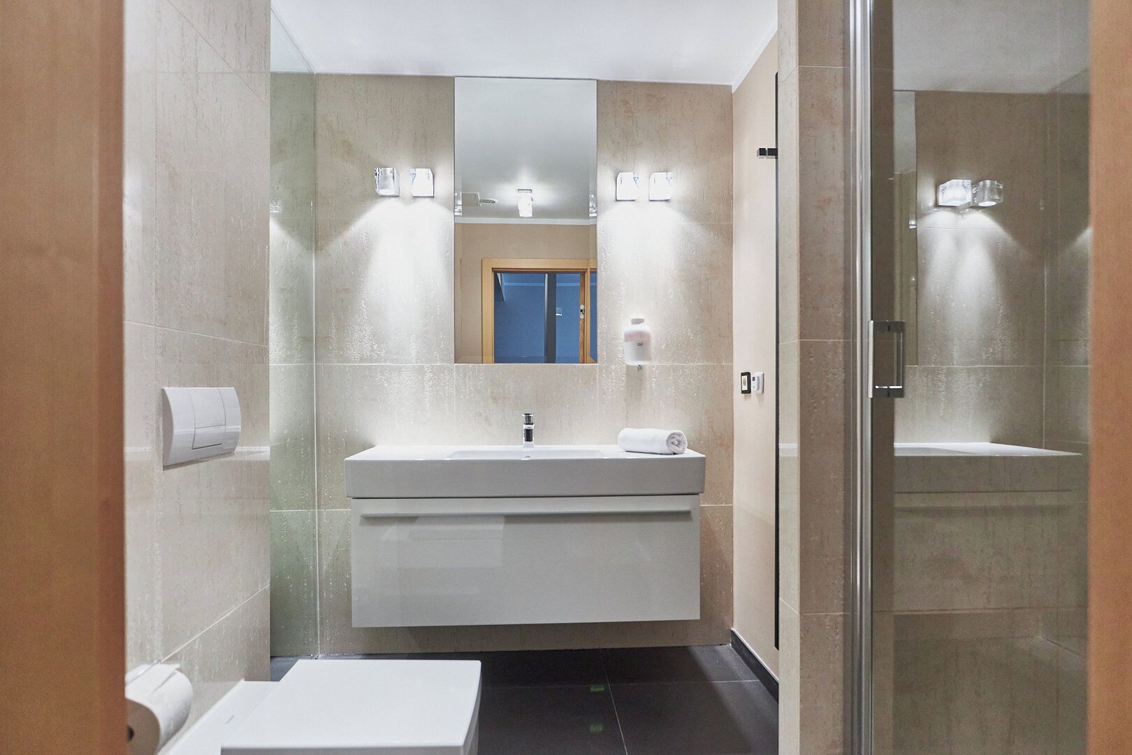 A modern bathroom with a white sink, mirror, and glass shower enclosure.