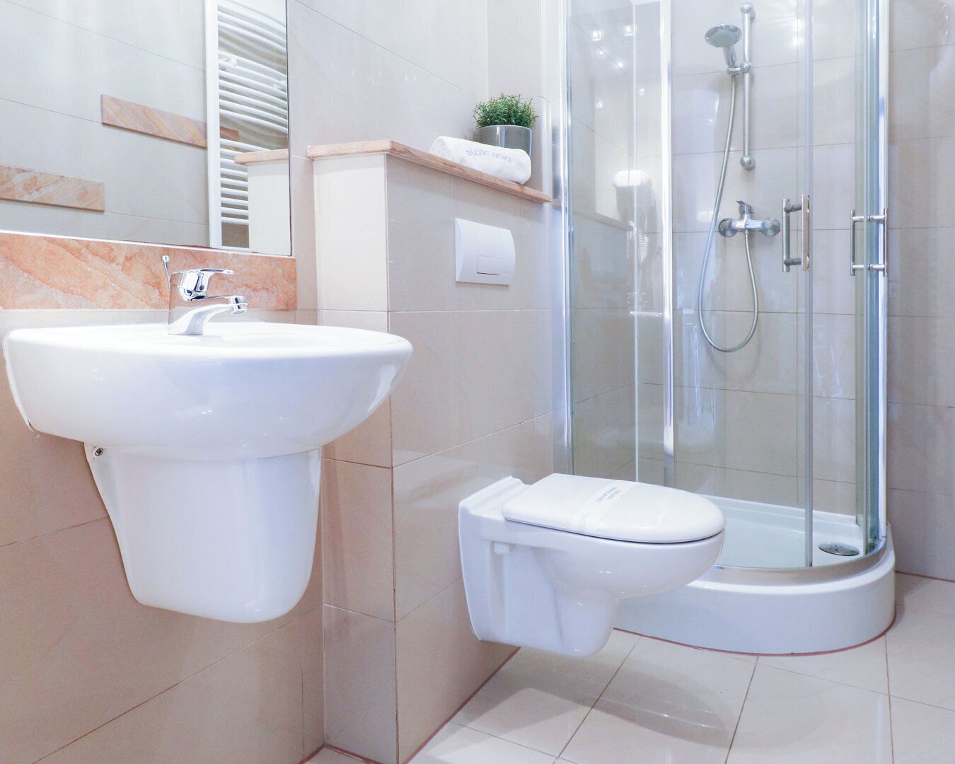 Et moderne badeværelse med et konsolbord, toilet og en brusekabine med glasvægge.