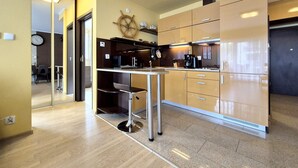 A modern kitchen with a central island, wooden cabinets, and a ship's wheel decoration. - Stella Baltic by Baltic Home (Swinoujscie)